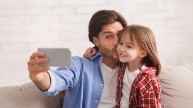 Yakışıklı baba, güzel kızını öperken birlikte selfie çekiyor, ev içi, fotokopi odası.