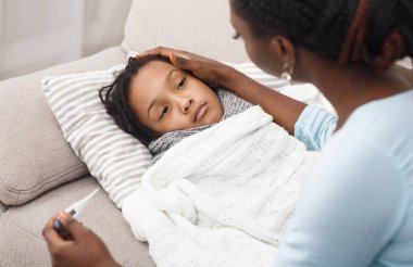 Ateş Konsepti. Hasta çocuk yatakta, annesi termometreyi tutuyor, zavallı kızı teselli ediyor.