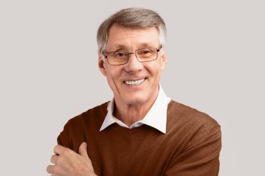 Gri arka planda kameraya gülümseyen yaşlı adamın portresi. Stüdyo Çekimi