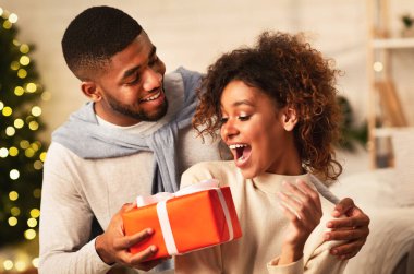 Xmas sürprizi. Afro adam kız arkadaşına Noel hediyesi veriyor, birlikte tatilleri kutluyor.