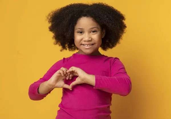 stock image Love Concept. Adorable Little African American Girl Showing Heart Gesture With Hands Over Yellow Background In Studio, Free Space