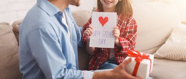 Baba ve kızı evde Babalar Günü 'nü kutluyorlar. Küçük kız kendi yaptığı kartı tutuyor, babası hediye kutusu taşıyor.
