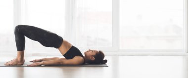 Paspasın üzerinde uzanan, iyi ışıklandırılmış bir yoga stüdyosunda sakin bir ifadeyle meditasyon yapan, uzayı kopyalayan bir insan.