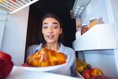 Dolapta taze kruvasana bakan aç kız, içeriden manzaralı.