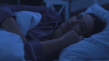 Geceleri uykusuzluk çeken, yatakta uyuyamayan bir kadın.