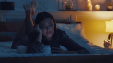 Uykusuzluk. Sıkıcı genç kadın cep telefonuyla iletişim kuruyor, gece geç saatlerde yatakta uzanıyor.