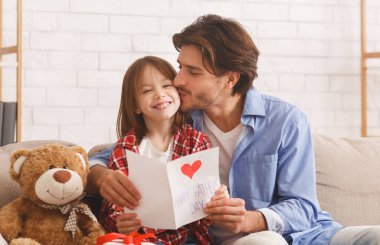 En iyi hediye sensin. Mutlu baba gülen kızını öpüyor Babalar Günü 'nde, iç mekanda, kopyalama alanında