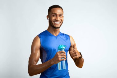 İyi antrenmandı. Kulaklık takmış, elinde su şişesi tutan mutlu zenci portresi.