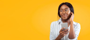 Pembe arka planda duran telefon ve kulaklık kullanan Afrikalı Amerikalı kız. Stüdyo Çekimi