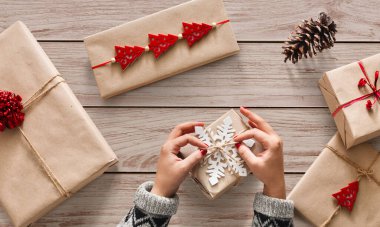 Yaratıcı hobi. Kadının ellerini şal Noel tatil Kraft kağıt sicim kurdele ile el yapımı mevcut. Xmas hediye kutusu, yay yapma, kar tanesi ile dekore edilmiştir. Beyaz ahşap masa, en iyi görünüm için makaslar.