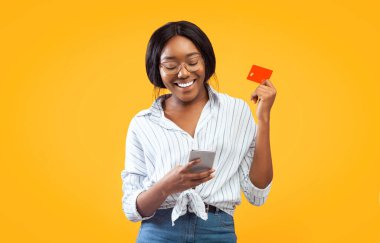 Mobil Bankacılık. Cep telefonu ve kredi kartı kullanan afro kız pembe arka planda duruyor. Stüdyo Çekimi