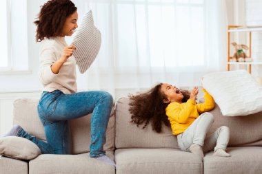 Jofyl Black Mother ve kızı yastıklarla kavga ediyor. Evde birlikte oynayarak eğleniyorlar. Seçici Odaklanma