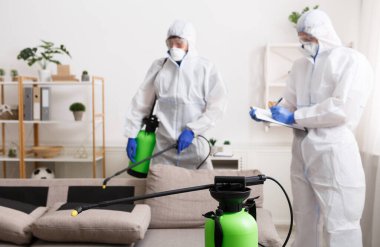 Anti koronavirüs dezenfeksiyonu. Koruyucu giysili adamlar evi temizliyor, salgın hastalık, karantina