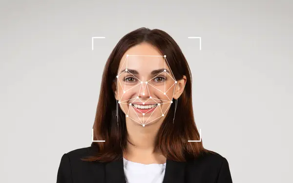 stock image A woman in professional attire smiles as facial recognition patterns are superimposed on her face.