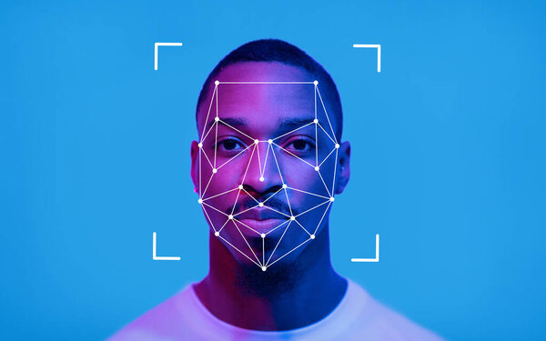 Лицо афроамериканца освещено синим светом, в то время как цифровая система распознавания лиц накладывает его черты, демонстрируя технологию в действии..