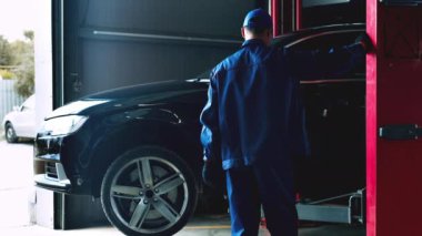 Servis çalışanı servis atölyesinde bakım yapılmadan önce aracı kaldırıyor.