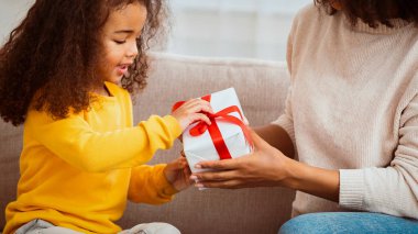Aile anları. İçerideki koltukta oturan annesinden hediye alan tatlı küçük bir kız. Kırpılmış, Panorama