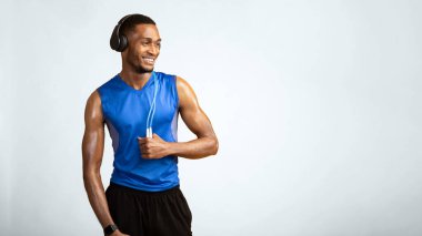 Zıplayan ipli Afrikalı kaslı adam sarı arka planda kulaklıkla müzik dinliyor. Panorama, kopyalama alanı