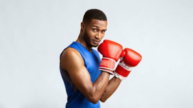 Boks Stance. Kırmızı eldivenli kaslı siyah adam sarı stüdyo duvarından izole edilmiş kameraya bakıyor.