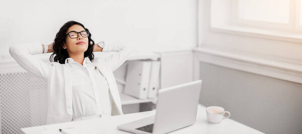 Break Time. Mexican designer relaxing, feeling satisfied, leaning back at workplace, free space