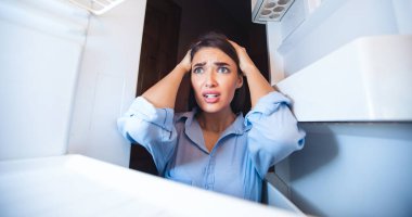 Yoksulluk kavramı. Çaresiz kadın evde boş buzdolabına bakıyor, içeriden bakıyor.