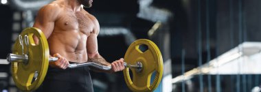 Ağırlık kaldırma. Spor salonunda halterle egzersiz yapan kaslı vücut geliştirici. Kopya alanı olan panorama.