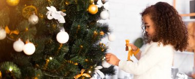 Küçük yardımcı. Evde Noel ağacı süsleyen tatlı afro kız, panorama, boş yer.