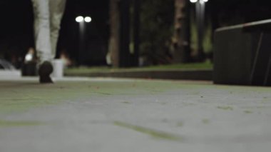 Spor ayakkabılı erkek bacaklarının gece parkında ağır çekimde yürürken yakın plan çekimi.
