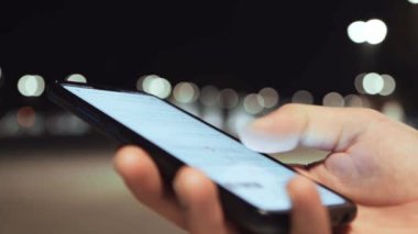 Modern akıllı telefonun erkek ellerinde yakın plan görüntüsü, akşam parkında sosyal medya ekranı olan adam.