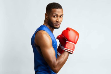 Atletik Siyah Savaşçı Boks Duruşunu Gösteriyor, Yumrukları Kaldırıyor, Sarı Stüdyo Arkaplanı. Yan görünüm, boş alan