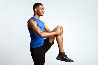 Isınmaya başla. Yüksek diz egzersizi yapan afro adamın yandan görünüşü, sarı arka plan üzerinde bacak kaldırma, kopyalanma alanı