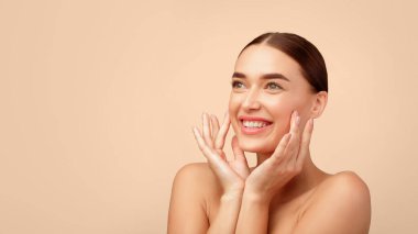 Cilt Bakımı Lezzeti. Gülümseyen, gülümseyen, yumuşak tenli, yüz güzelliğine önem veren açık gri stüdyo arka planında üstsüz poz veren neşeli genç bir kadın. Boşluğu Kopyalayan Panorama