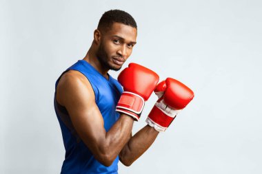 Dövüşçü. Atletik siyah adam boks duruşunda kameraya bakıyor, sarı stüdyo geçmişi var. Yan görünüm, boş alan