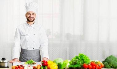 Üniformalı Erkek Şef, Mutfakta Duran Kameraya Gülümsüyor. Profesyonel Aşçı Portresi. Seçici Odaklanma