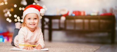Noel Baba 'ya mektup. Küçük kız dilek listesi yazıyor, Noel ağacının yanında yerde yatıyor, boş bir yer.