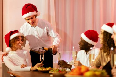 Noel arifesi. Şampanya servisi yapan adam kadehleri doldurup arkadaşlarıyla Noel 'i kutluyor.