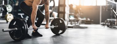 Zor bir çalışma. Kas kaldırıcı spor salonunun zemininden ağır halteri kaldırıyor, boş alan, kesilmiş.