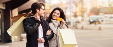 Butik alışverişi yapan çiftler, kredi kartı gösteren kadınlar, çantalar, fotokopi alanı olan panorama.