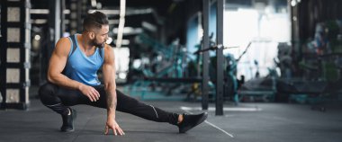 Spor salonundaki sporcu bacaklar için esneme egzersizleri yapıyor, boş alan, panorama