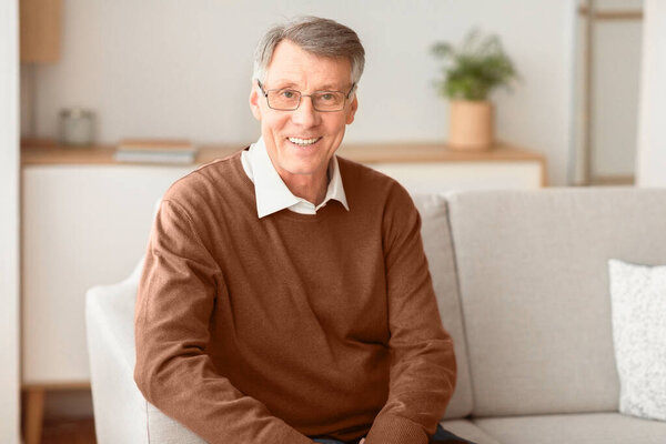 Happy Retired Man. Smiling Senior Gentleman Looking At Camera Sitting On Couch At Home.