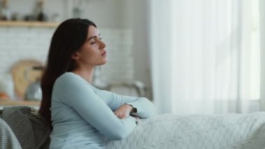 Sonbahar depresyonu. Genç üzgün kadın evde tek başına oturuyor, yan tarafa bakıyor, kötü ruh hali, yan görüş, ağır çekim