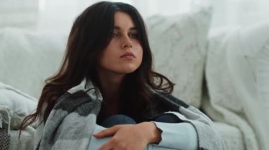 Ekoseye sarılmış, dizlerinin üstüne çöküp, hayat sorunlarını düşünen çaresiz genç kadının portresini yakından çek.