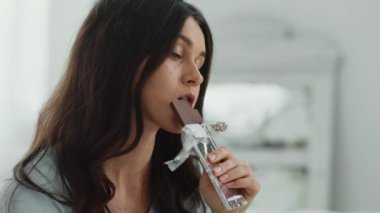 Stres nöbeti. Depresyonda olan genç bir kadının çikolata yerken, evde çikolata yerken, ağır çekimde çekilmiş portresi.