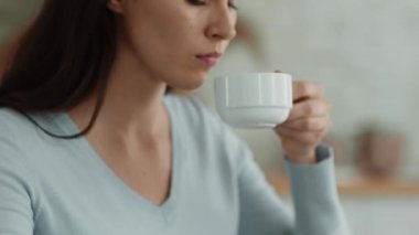 Melankolik genç bir kadının çay içerken, sıcak içecekle bardağı tutarken, depresyondan acı çekerken görüntüsü. Ruh hali değişimleri ya da psikolojik sorunlar kavramı