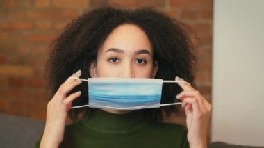 Yeni normal ve kişisel koruma. Genç Afro-Amerikan bayan dışarı çıkmadan önce koruyucu bir maske takıyor, portre yakın çekim, yavaş çekim.