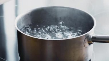 Kaynar su. Mutfak sobasında sıcak sıvı bulunan metal tavayı kapat.