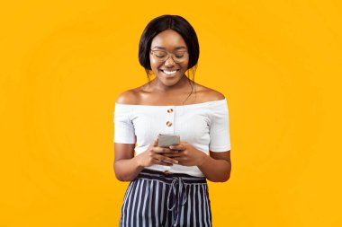 Gülümseyen Siyahi Kadın Sosyal medyada Arkadaşlarıyla Akıllı Telefon Sohbeti Yapıyor Turuncu Arkaplanda Duruyor. Stüdyo Çekimi