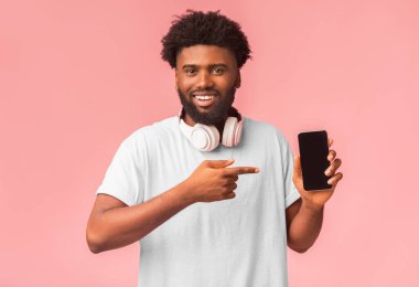 Cep telefonunu öneririm. Modern Afrikalı Amerikalı adam boş ekran ile en yeni cep telefonunu işaret ediyor, boş alan ile pembe arka plan