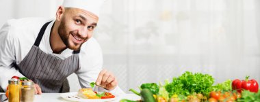 Smiling Chef Man Decorating Roasted Salmon Steak With Herbs Standing In Kitchen. Selective Focus