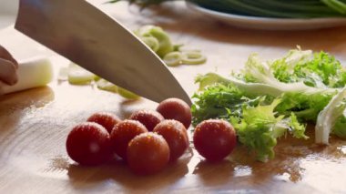 Kadın vejetaryen salatası hazırlıyor, mutfak masasında taze sebze kesiyor.